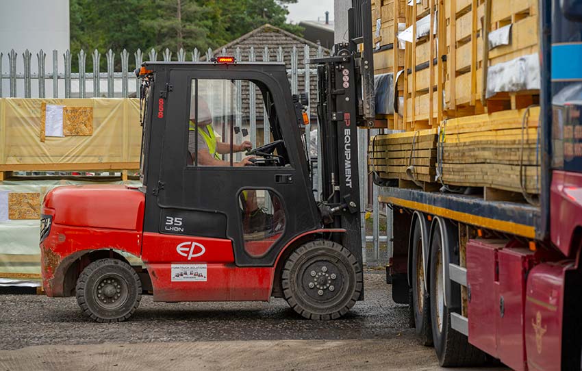 Timber frame kit being loaded onto lorry by forklift